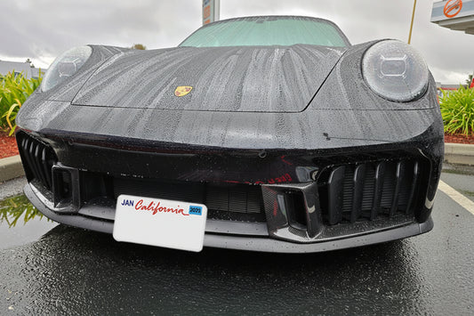 Front view of a black sports car with a visible license plate in an outdoor setting.